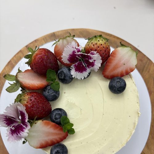 Vanilla cake with fresh strawberries blueberries and edible flowers Crème It Up